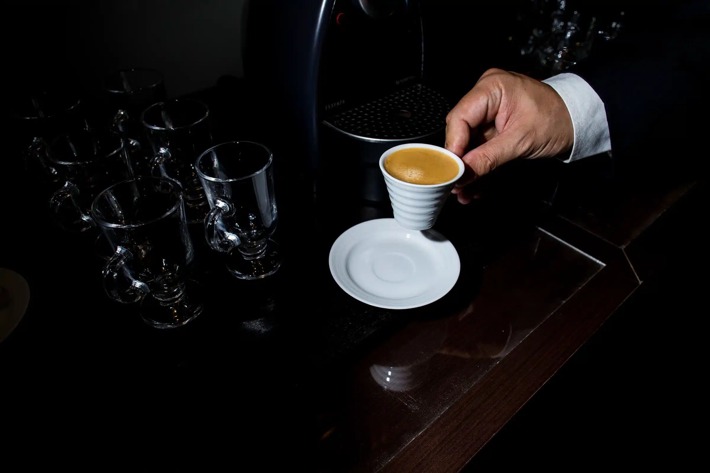 Xícara de café sendo servida no balcão escuro da sala de reunião do escritório.