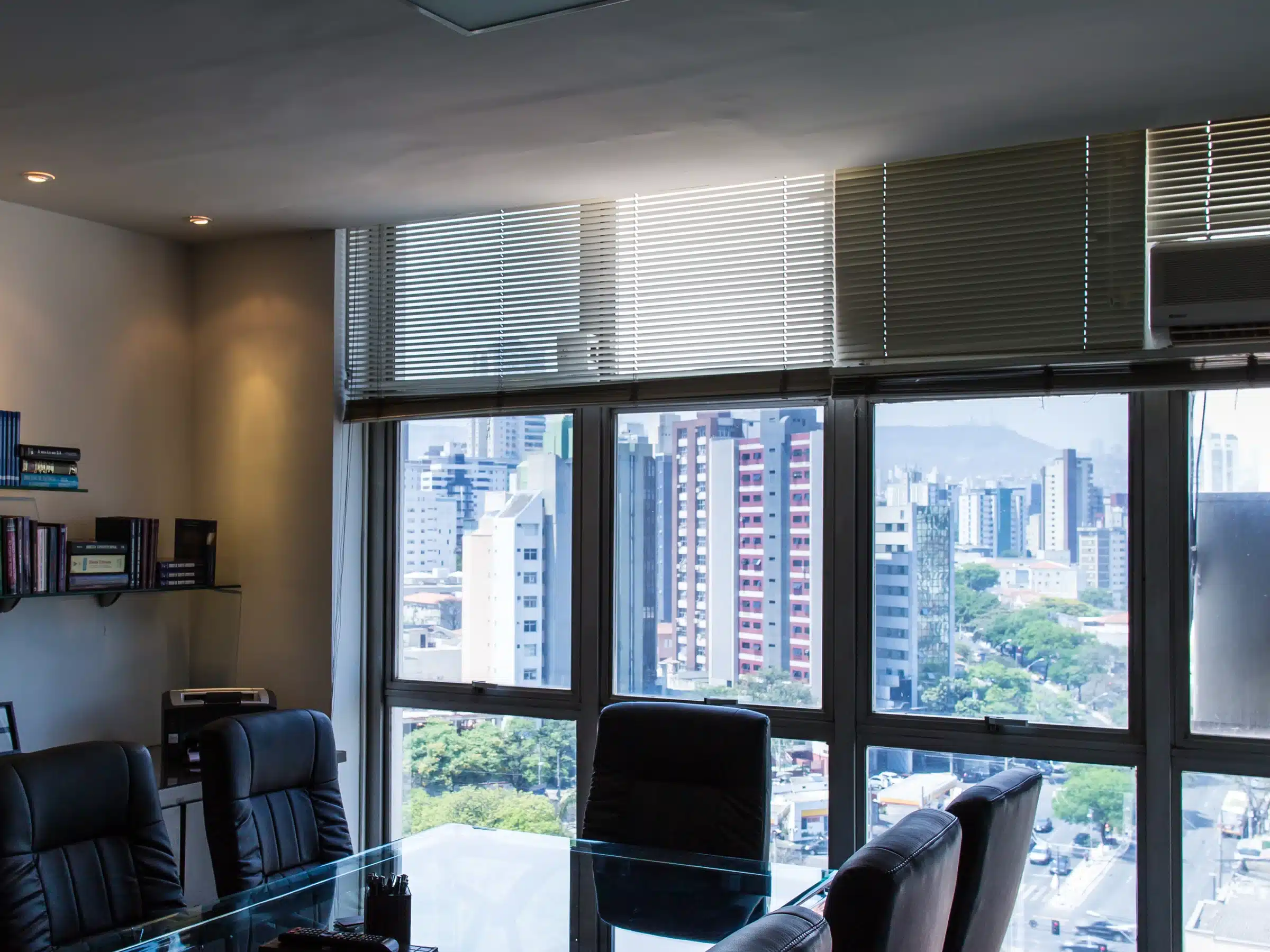 Sala de reunião do escritório em Belo Horizonte, com vista da cidade pela janela.